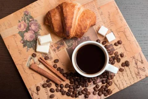 Cup of coffee, croissant, coffee grains, cinnamon, sugar and chocolate Stock Photos