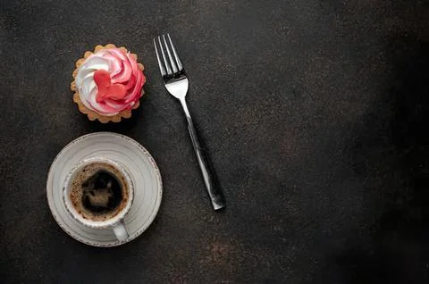 Cup of coffee with a cupcake and fork on dark background Stock-Fotos