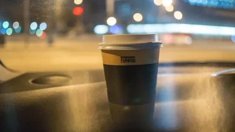A cup of coffee is on the dashboard of the car Stock Photos