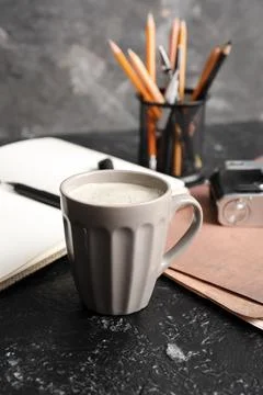 Cup of coffee with documents and camera on black grunge background, closeup Stock-Fotos