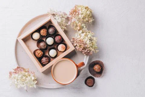 Cup of coffee drink a box of various chocolates on a ceramic dish on the table Stock Photos