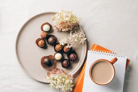 Cup of coffee drink a box of various chocolates on a ceramic dish on the table Stock Photos