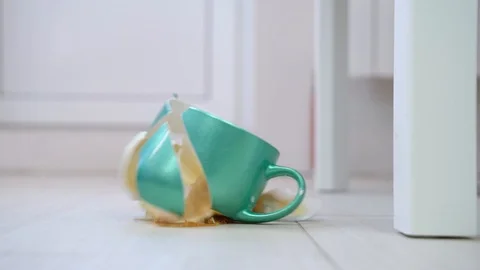 A cup of coffee falls to the floor from the table, breaks into many pieces. Stock Footage 117252527