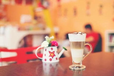 Cup of coffee with flower lobe pattern in reveal cup on wooden table. Stock Photos