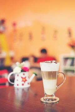 Cup of coffee with flower lobe pattern in reveal cup on wooden table. Stock Photos