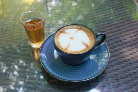 A cup of coffee with flower pattern in a blue cup on mirror Stock Photos