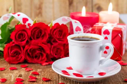 Cup with coffee in front of bouquet of red roses 库存照片