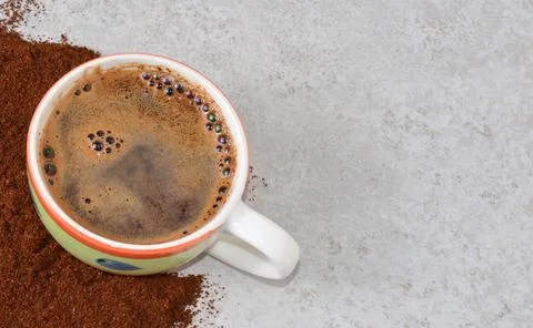 A cup of coffee on a gray table around spilled coffee. Stock Photos