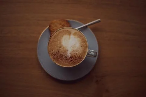 Cup of coffee with a heart pattern in a cup on a saucer on a wooden background Stock Photos