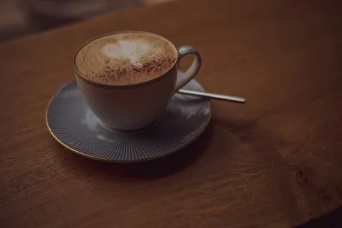 Cup of coffee with a heart pattern in a cup on a saucer on a wooden background Stock Photos