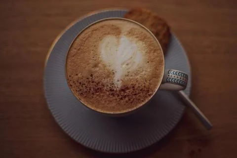 Cup of coffee with a heart pattern in a cup on a saucer on a wooden background Stock Photos