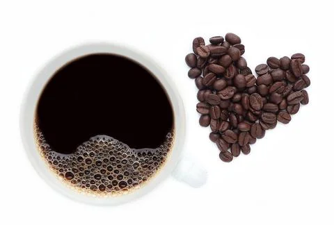 Cup of coffee isolated on white background with coffee beans in heart shape. Stock Photos