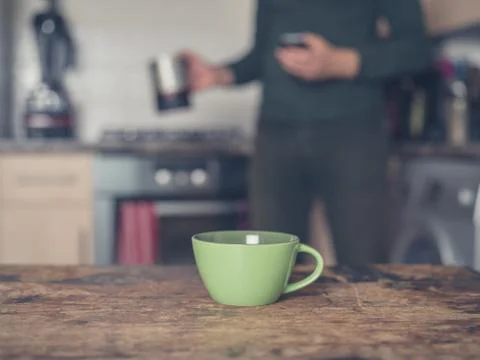 Cup of coffee in kitchen with man in background Photos