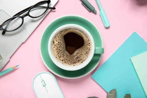 Cup of coffee with laptop, computer mouse, notebooks and eyeglasses on pink b Stock Photos