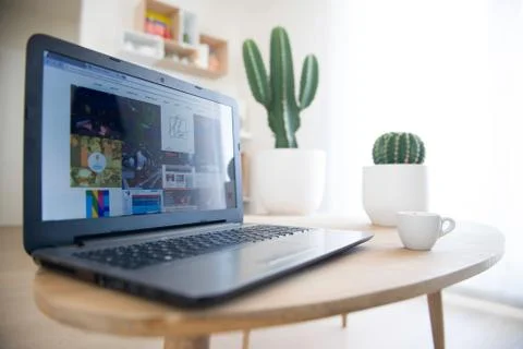 A cup of coffee with a laptop computer on table in a modern interior with cactus Foto stock