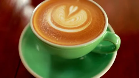 A cup of coffee with latte art on table at cafe. morning coffee with milk. 動画素材 334650585
