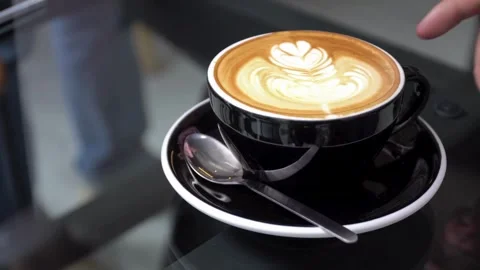 A cup of coffee with latte art on table at cafe. morning coffee with milk. 動画素材 334650658