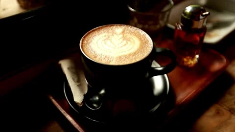 A cup of coffee with latte art on table at cafe. morning coffee with milk. 動画素材 334650683
