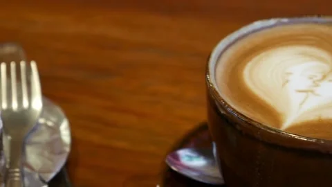 A cup of coffee with latte art on table at cafe. morning coffee with milk. 動画素材 334650797