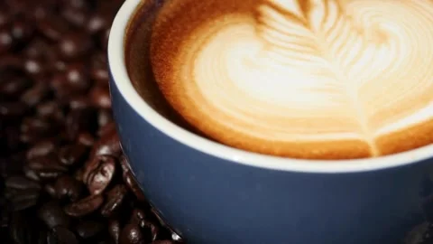 A Cup of coffee with latte art on top of coffee beans. Stock Footage 334648863