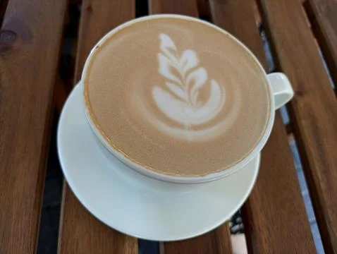 Cup of coffee with a leaf design on the foam Stock Photos
