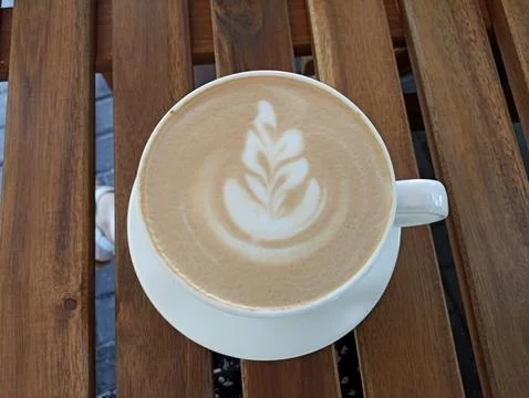 Cup of coffee with a leaf design on the foam Stock Photos