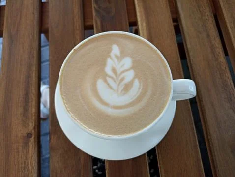 Cup of coffee with a leaf design on the foam Stock Photos