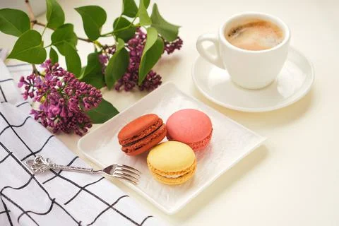 Cup of coffee with macaroons on a table with flowers Stock Photos