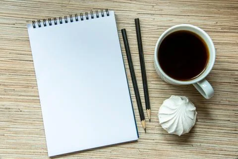 A cup of coffee with marshmallow, notebook with two pencils on wooden backgro Stock Photos