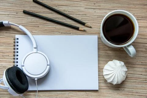 A cup of coffee with marshmallow, notebook with two pencils and white headpho Stock Photos