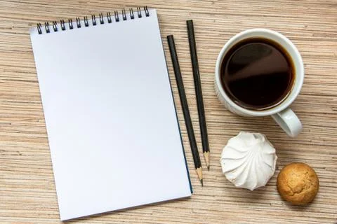 A cup of coffee with marshmallow, notebook with two pencils on wooden backgro Stock Photos