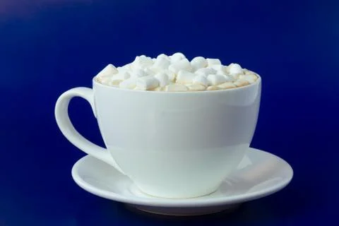 Cup of coffee with marshmallows on a blue background. Stock Photos