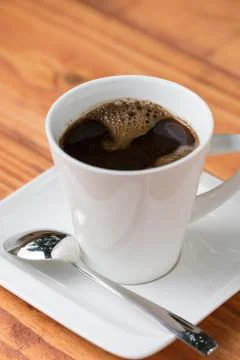 Cup of coffee with metal spoon on the table Stock Photos