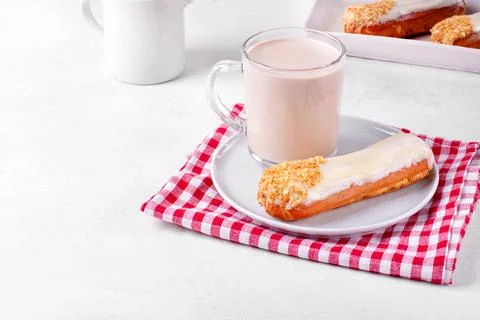 Cup of coffee with milk and eclair with icing Foto stock