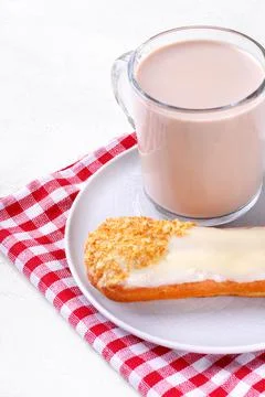 Cup of coffee with milk and eclair with white icing Foto stock