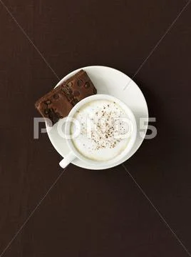 A cup of coffee with milk foam and a brownie (seen from above) Stock Photos