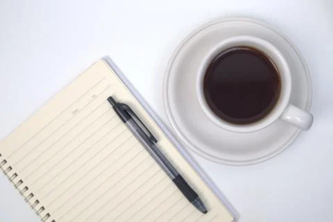 Cup of coffee, notebook and pen on white table Stock Photos