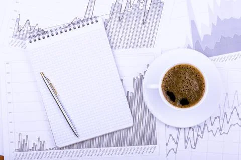 Cup of coffee, notepad  and graphs Stock Photos