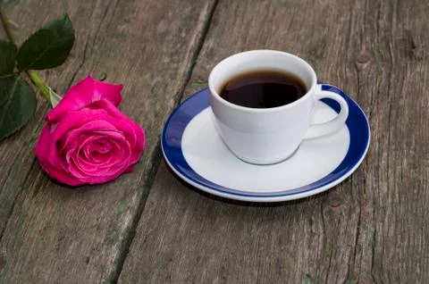 Cup of coffee on an old table and nearby a rose Stock Photos