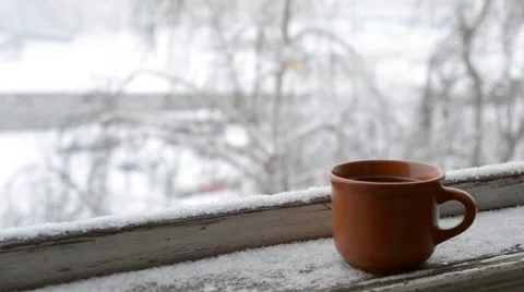 Cup of coffee on old window sill on background of falling snow Video stock 47037078