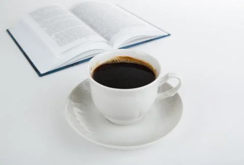 Cup of coffee with open book on white Stock Photos