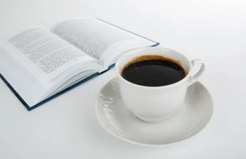 Cup of coffee with open book on white Foto stock