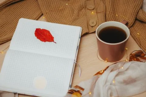 A Cup of coffee, an open diary on empty pages lie on the table, on which lies Stock Photos