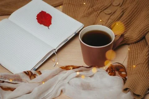 A Cup of coffee, an open diary on empty pages lie on the table, on which lies Stock Photos