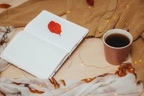A Cup of coffee, an open diary on empty pages lie on the table, on which lies Stock Photos