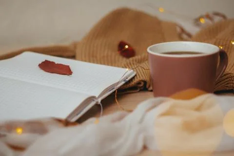 A Cup of coffee, an open diary on empty pages lie on the table, on which lies Stock Photos