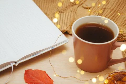 A Cup of coffee, an open diary on empty pages lie on the table, on which lies Stock Photos