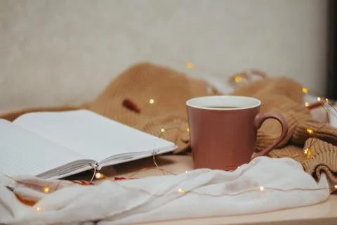 A Cup of coffee, an open diary on empty pages lie on the table, on which lies Stock Photos