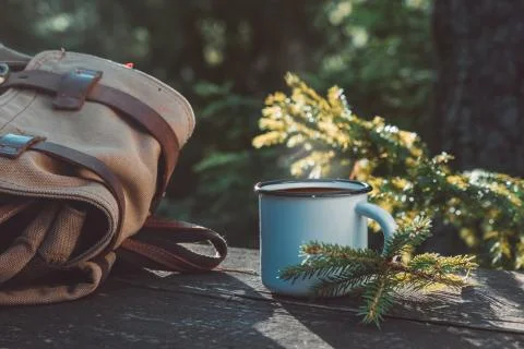Cup of coffee or tea, backpack of traveller on wooden board. Stock Photos