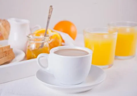 Cup of coffee or tea, bread toast with orange jam, glasses of orange juice on Stock Photos